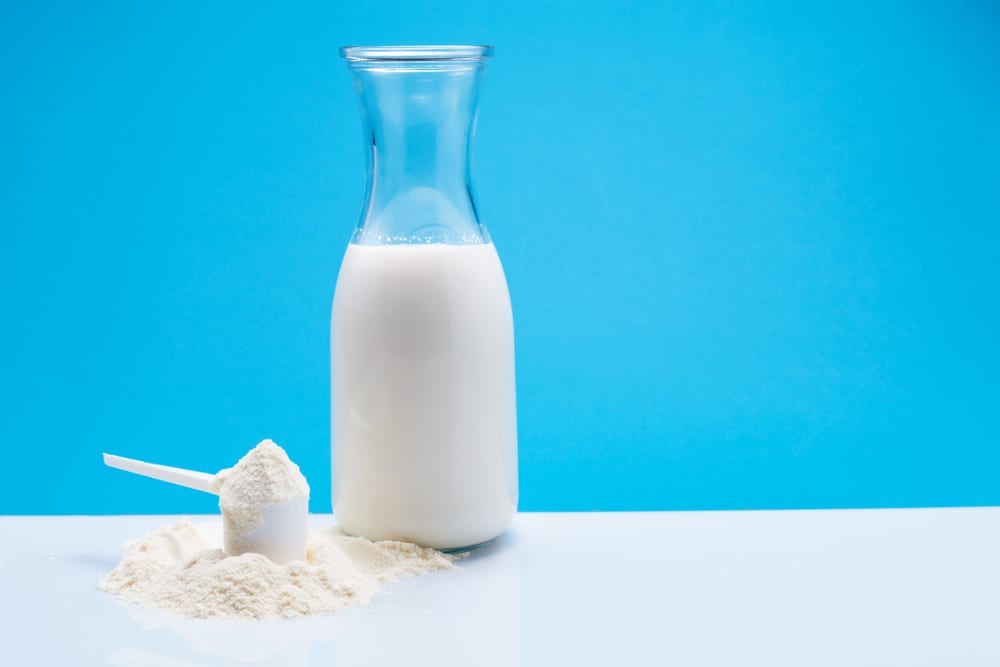 A bottle of milk beside a scoop of bone broth protein powder