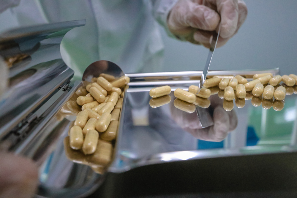 Technician handling capsules during the wet granulation water phase