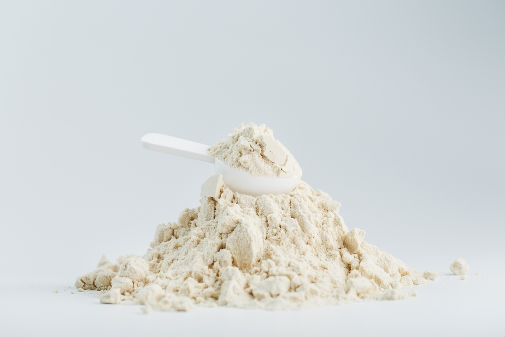 Scoop resting on a pile of free-flowing powder supplement mixture