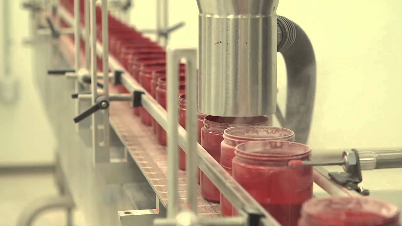 Filling machine dispensing supplement powder into bottles on a production line