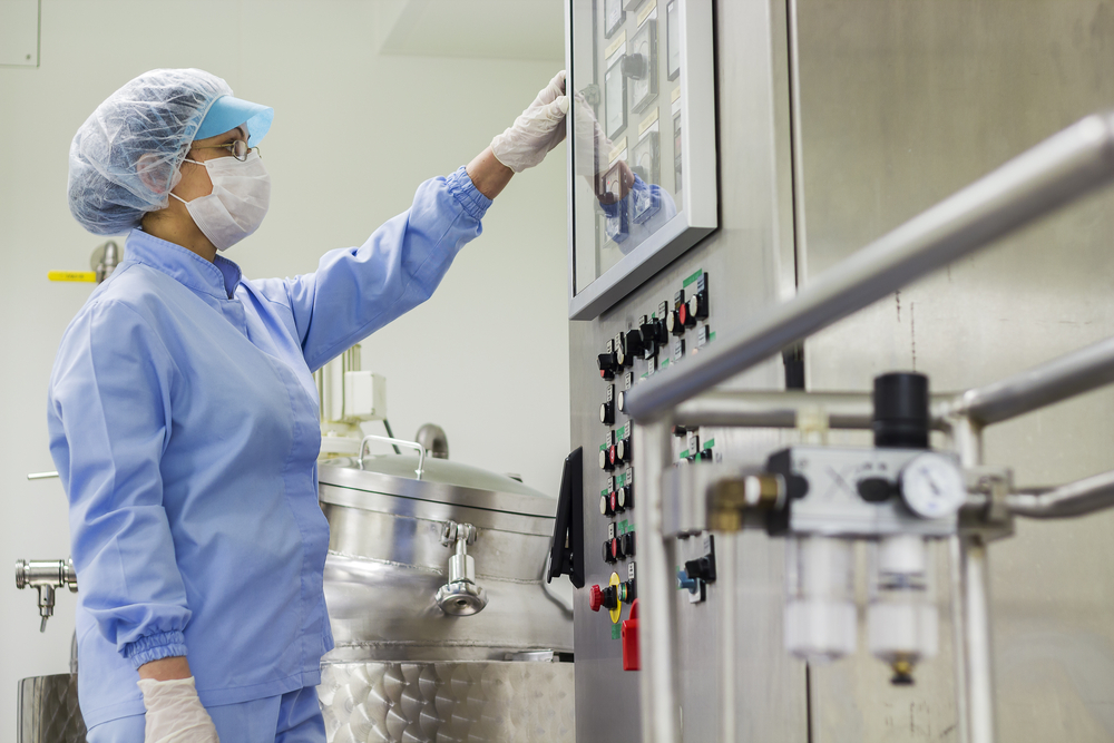 Technician operating manufacturing equipment while measuring powder supplement ingredients
