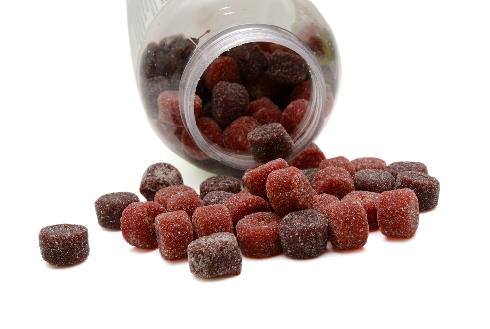 Button-shaped gummy vitamins spilling from an open supplement bottle