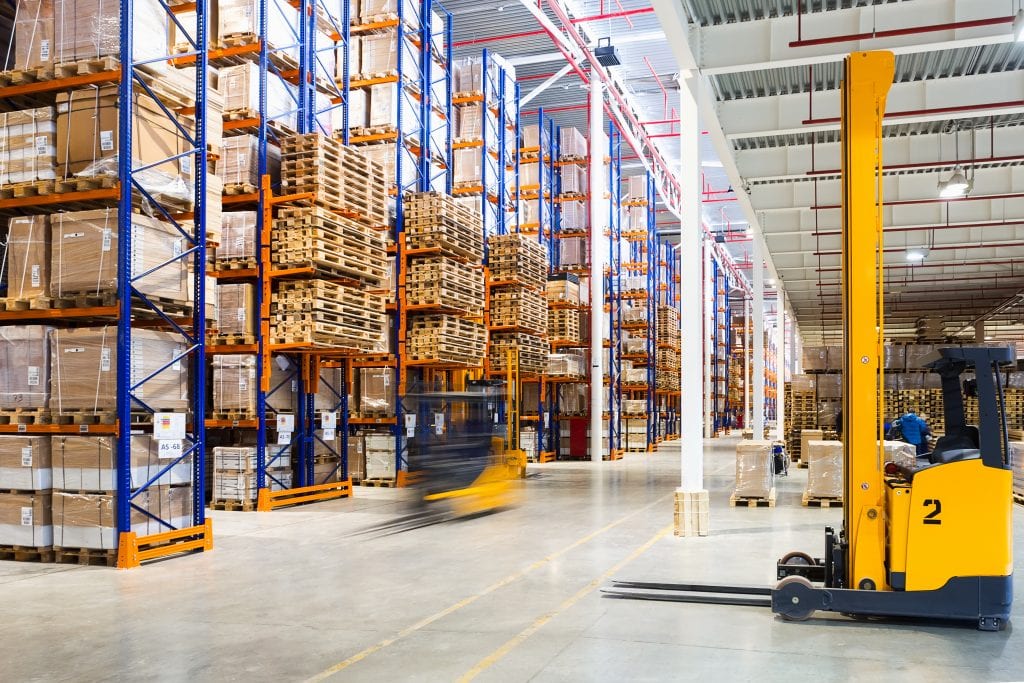 Forklift moving pallets of packaged product in a distribution warehouse