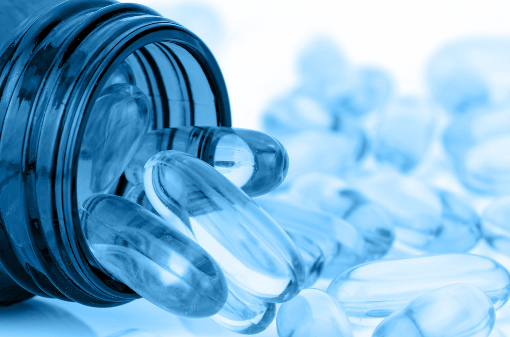 Softgel capsules spilling from an open supplement bottle