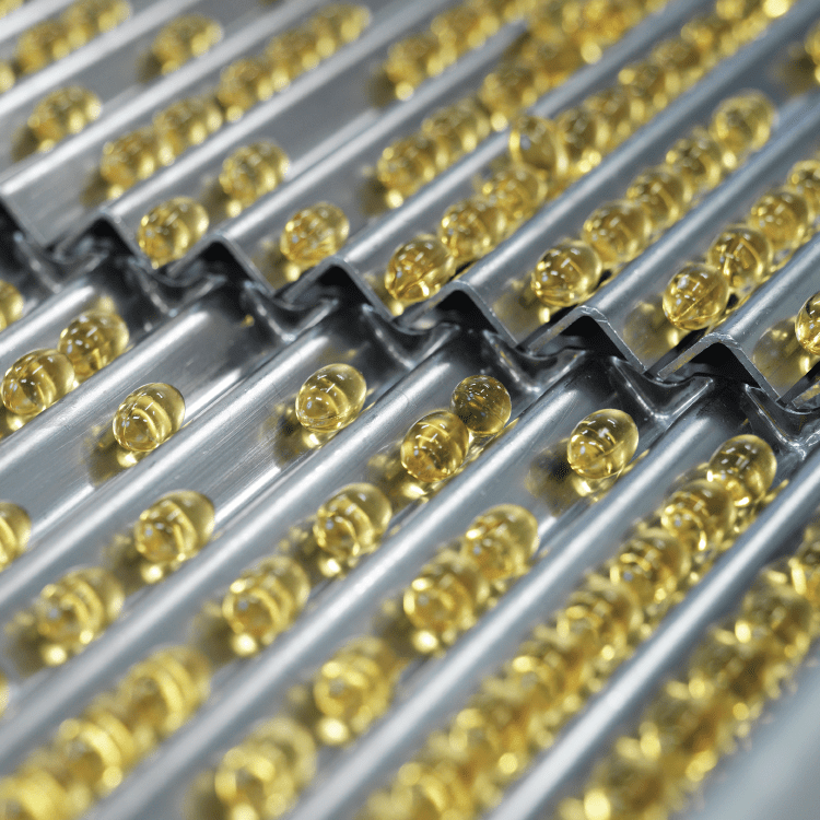 Rows of softgel capsules being sorted in automated sorting machinery
